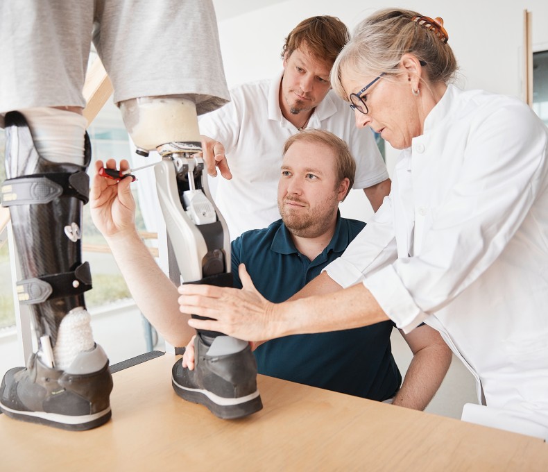 Ärztliches Personal passt bei einem Patienten eine Prothese des Unterschenkels an.