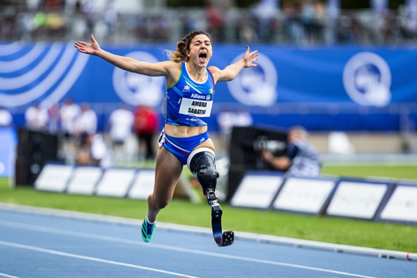 Das Foto zeigt die italienische Läuferin Ambra Sabatini. Sie läuft mit einer Beinprothese am linken Bein, reißt die Arme zur Seite und schreit vor Begeisterung.