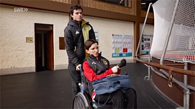 Lotta Berglung fährt mit einem Rollstuhl in den Eisring. Kurze, dunkle Haare, Schlankes Gesicht, Brille.